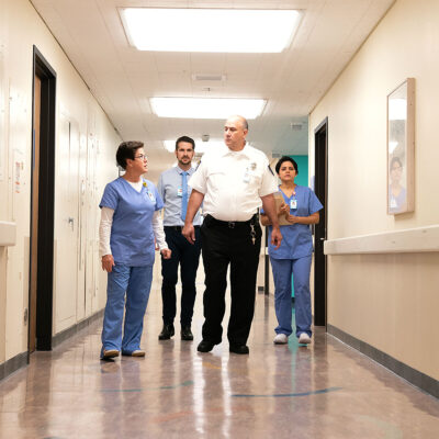 Security personnel walking with hospital staff in hallway | security leader webinar